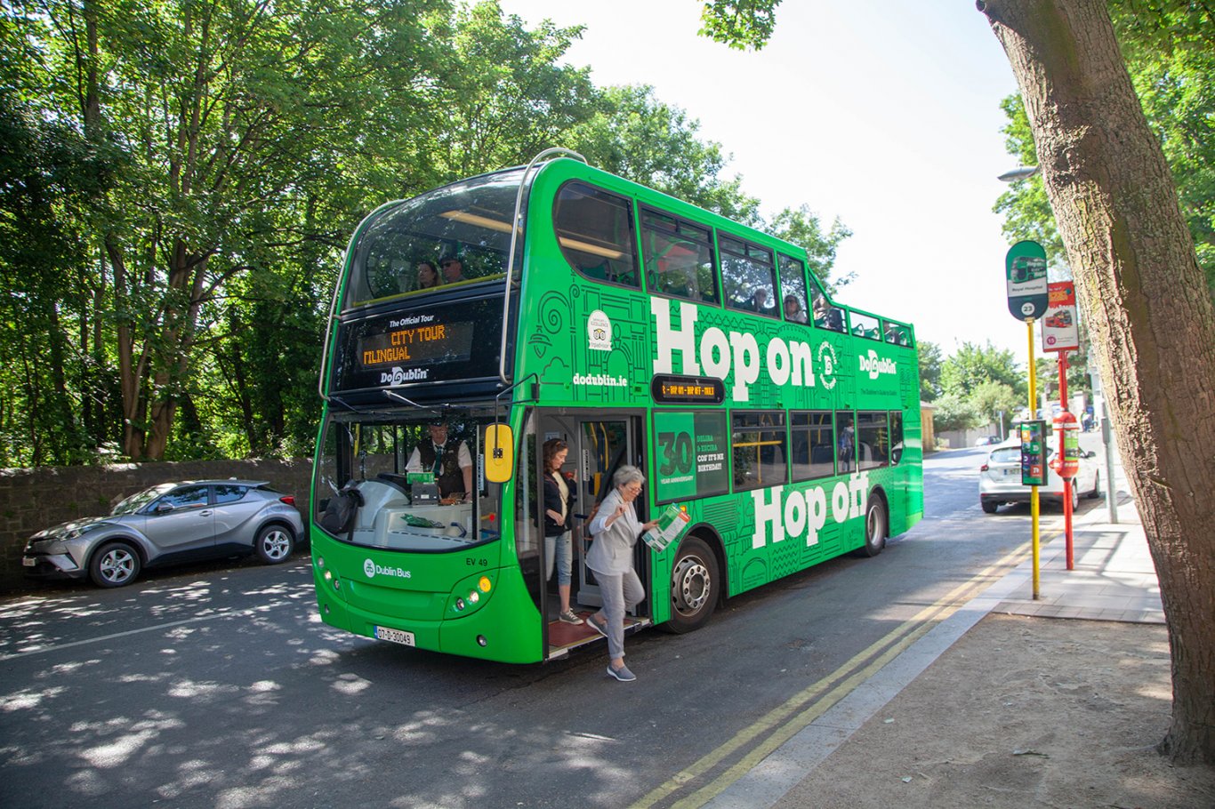 Passengers getting off double deck open top bus