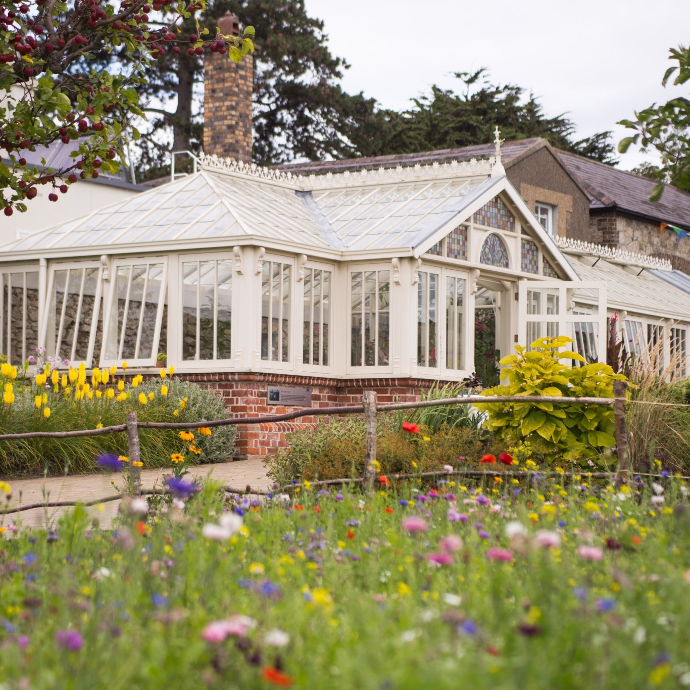 glass house surrounded by flower beds